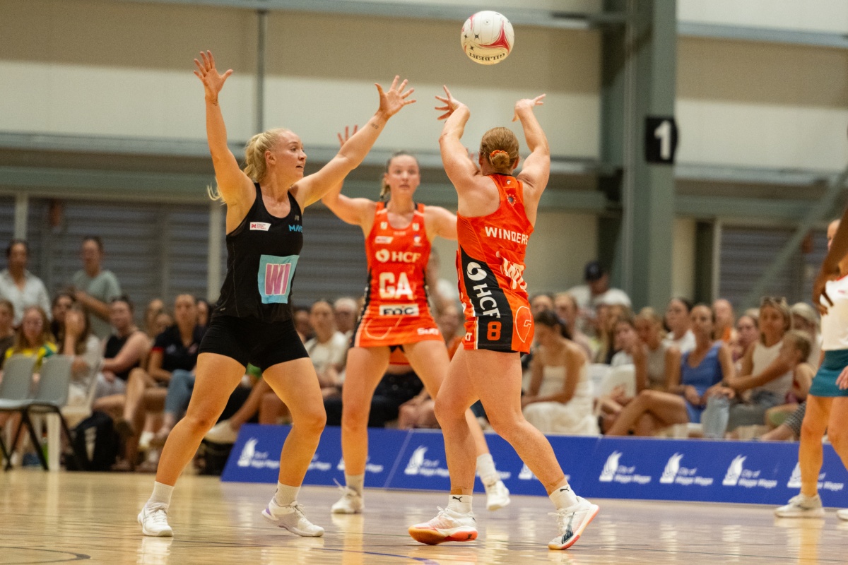 Netball players from opposing teams vying to catch a ball.