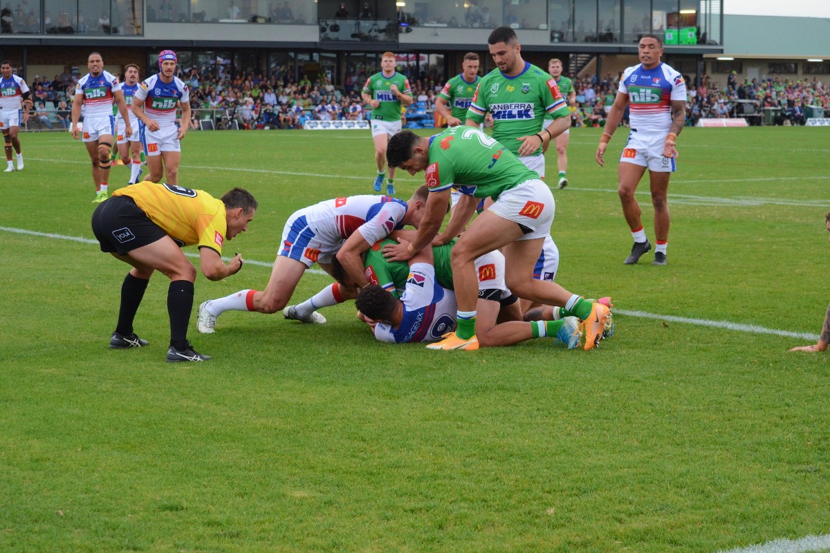 Football player in green jersey tackles a play in a white jersey during a league game.