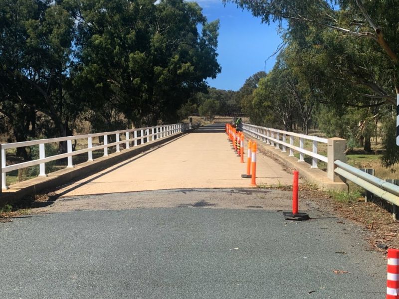 Rural bridge with traffic cones on the concrete deck, reducing the driving area to one lane.