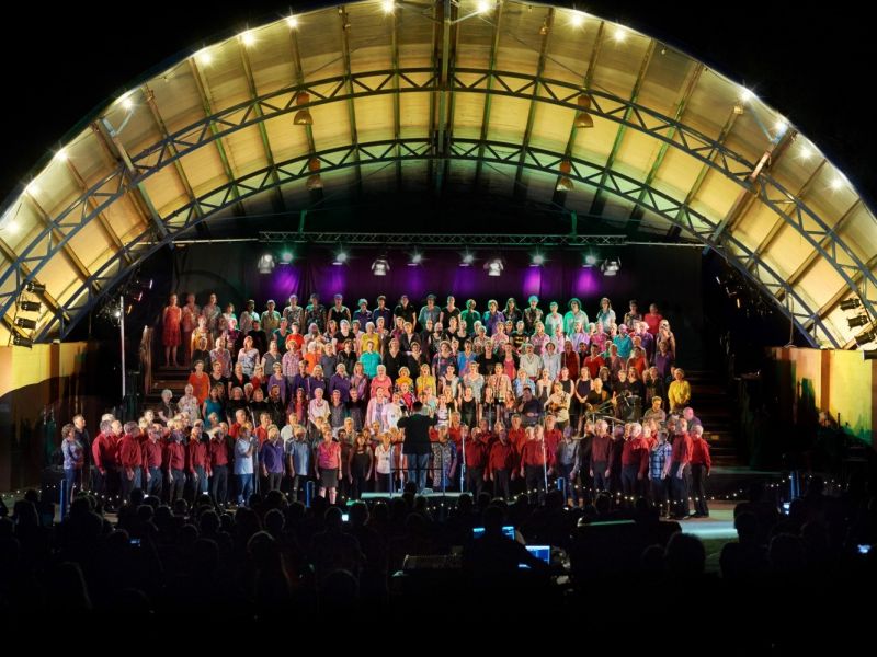 Choir on stage at night, with lights in arch over the top of the Music Bowl.