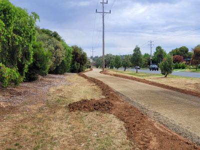 Earthworks and road base work on a shared path on the wide road verge in a residential area.