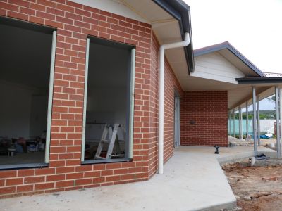 Exterior view of brick building under construction, with windows still to be installed.