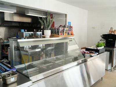 A photo of a newly rennovated, brightly lit commercial canteen space, with white tiled walls and a stainless steel glass display cabinet in the foreground.