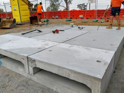 Two men in hi-vis shirts on a work site, working on the installation of large concrete culverts under a foot and cycle path.